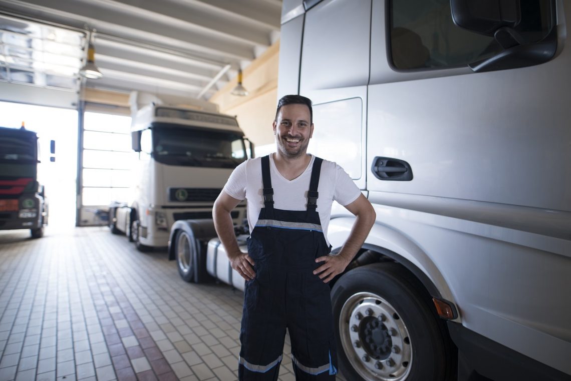 smiling mechanic in front of trucks